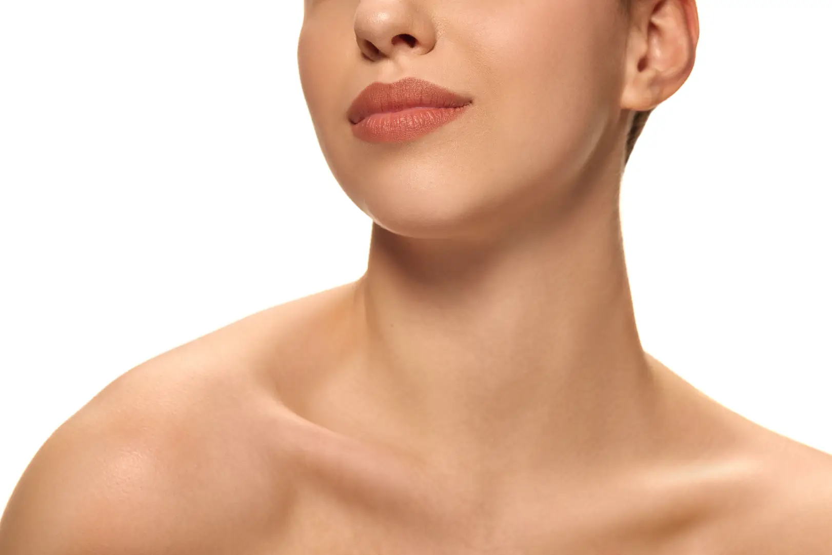 Lower face, jawline, neck, and shoulders of a person against a light background.